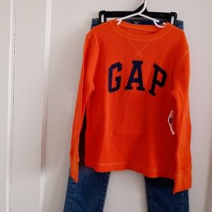 Denim jeans with an orange and blue thermal shirt.